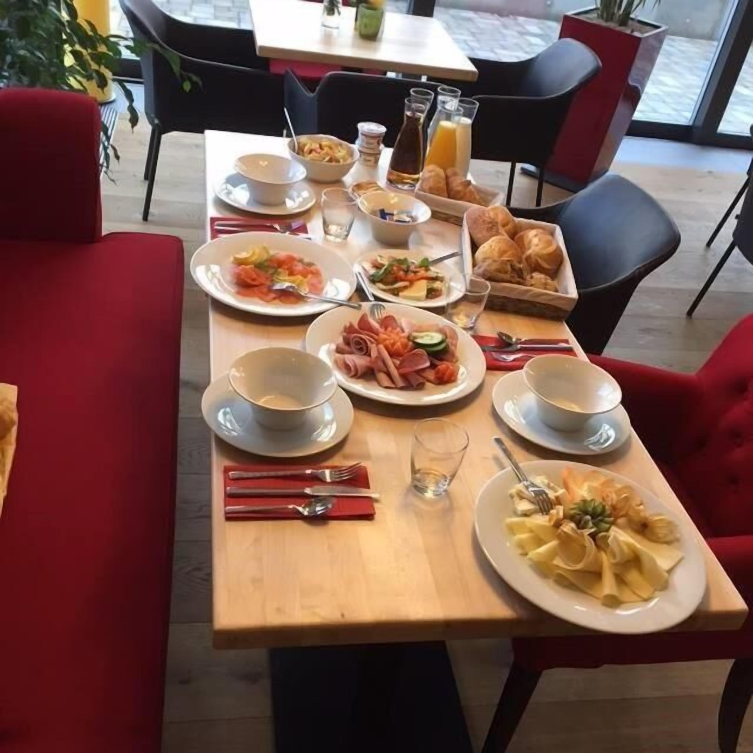 A breakfast table set with plates of food, cups, and cutlery.