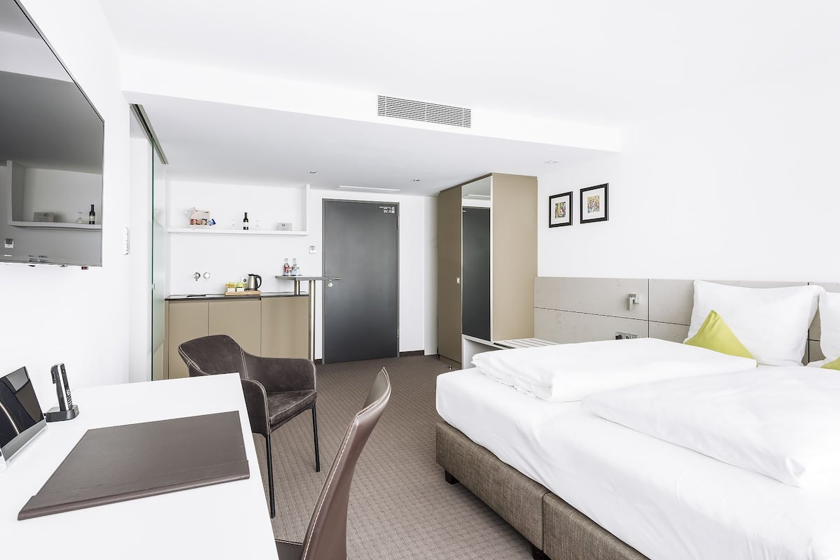 A hotel room with a bed, a desk, a chair, a wardrobe, and a bathroom.