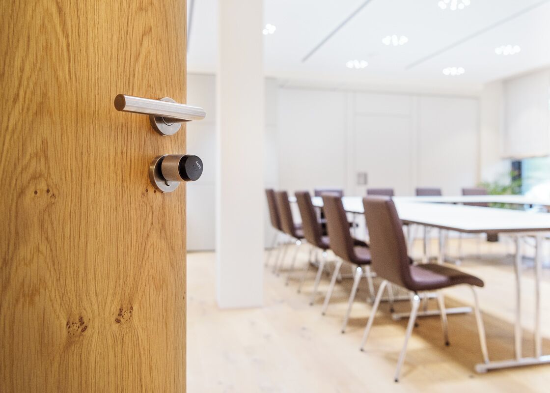 Une salle de conférence avec une porte en bois, une serrure moderne et une rangée de chaises.