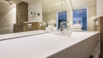 A modern bathroom with a large mirror, a shower, and a sink.