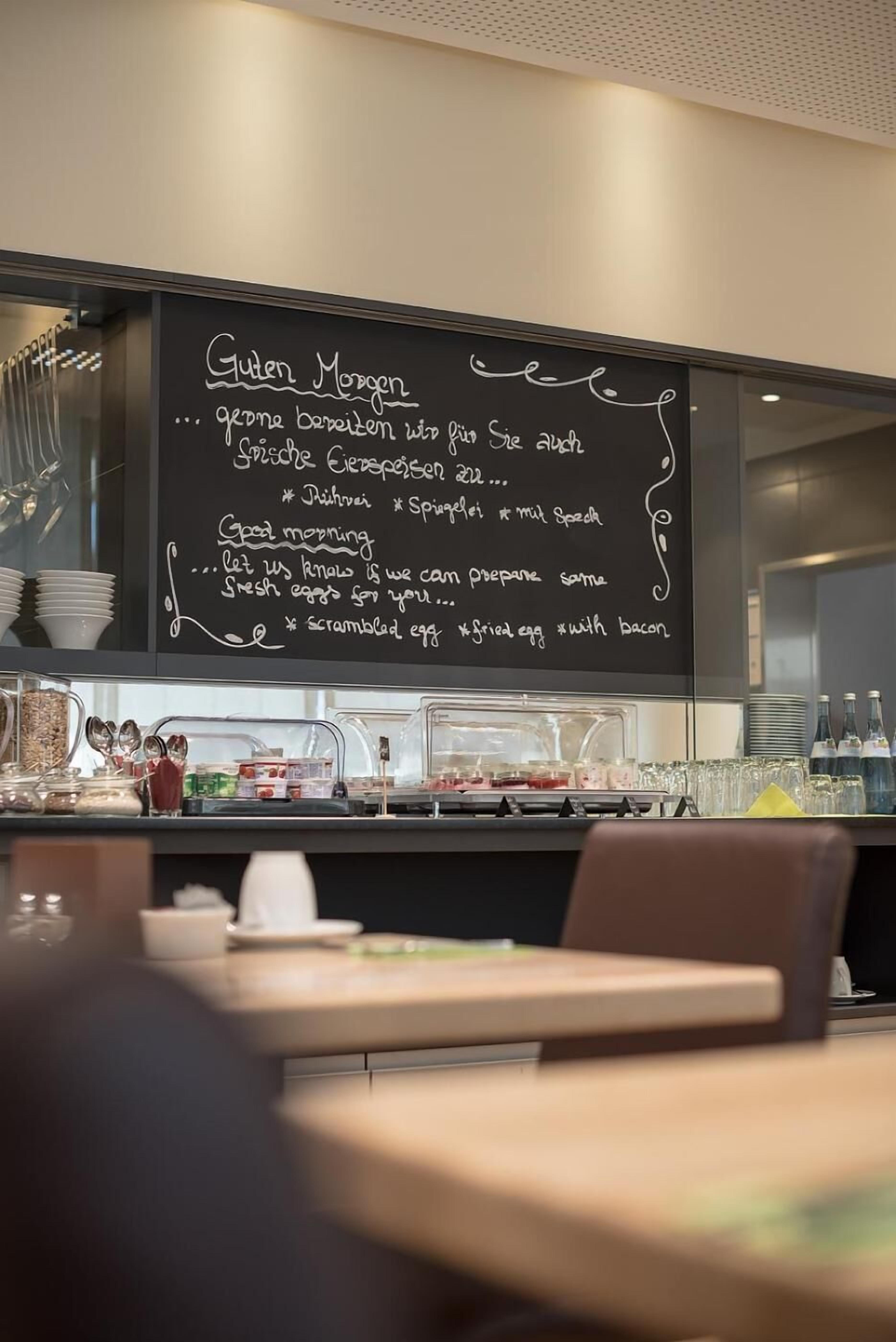 Ein Frühstücksbuffet mit einer Kreidetafel, auf der Speisen wie Rührei und Speck aufgeführt sind.