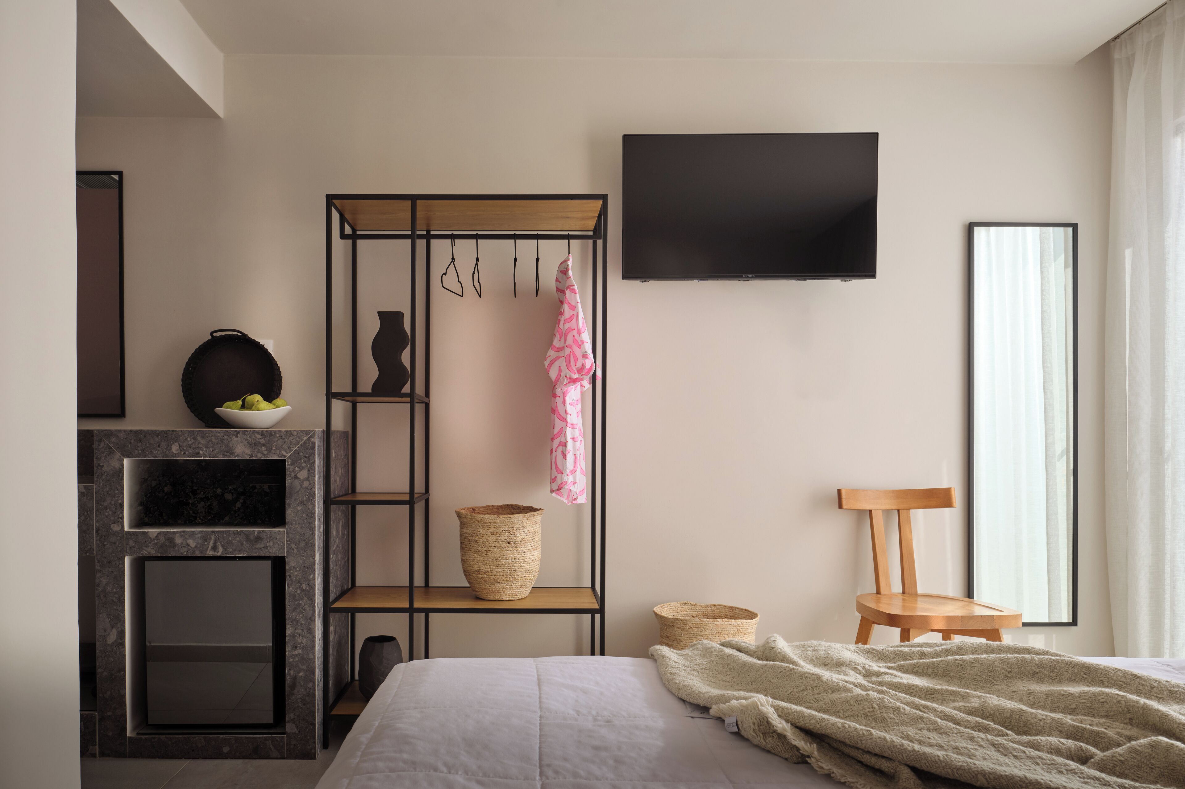 A modern bedroom with a bed, a TV, a fireplace, and a wooden chair.