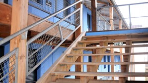 A wooden staircase with metal railings leading to a blue building with multiple levels. - UNISOTEL Le Havre (Le Havre)