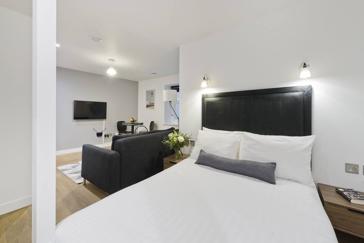 Una camera d'hotel moderna con un letto grande, una scrivania, una TV a schermo piatto e un piccolo angolo salotto.