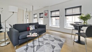 Una sala de estar moderna con un sofá gris, una mesa de centro redonda y una mesa de comedor negra con sillas.