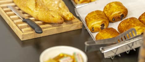A kitchen counter with various baked goods, including bread and pastries, and a cutting board with a knife.