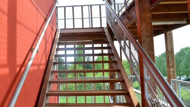 A wooden staircase with metal railings leading to an upper level. - Unisotel Le Mans (Le Mans)