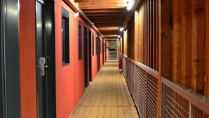 A corridor with red walls, black doors, and a wooden floor. - Unisotel Le Mans (Le Mans)