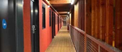 A corridor with red walls, black doors, and a wooden floor.