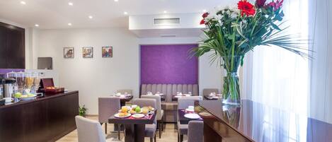 Ein Hotel-Essbereich mit Tischen, Stühlen, einer Rezeption und einer großen Blumenvase.