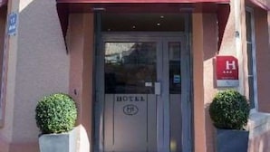A hotel entrance with a red awning labeled "HOTEL JENNER" and a sign indicating the hotel name. - Hôtel Jenner (Paris)