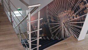 A staircase with metal railings and a mural of a Ferris wheel. - Hôtel Jenner (Paris)