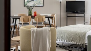 A modern living room with a dining area, a flat-screen TV, and a painting on the wall. - Cove St Martin’s (London)