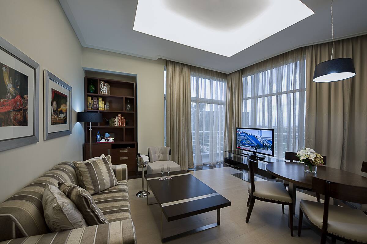A modern living room with a sofa, coffee table, TV, and dining area.