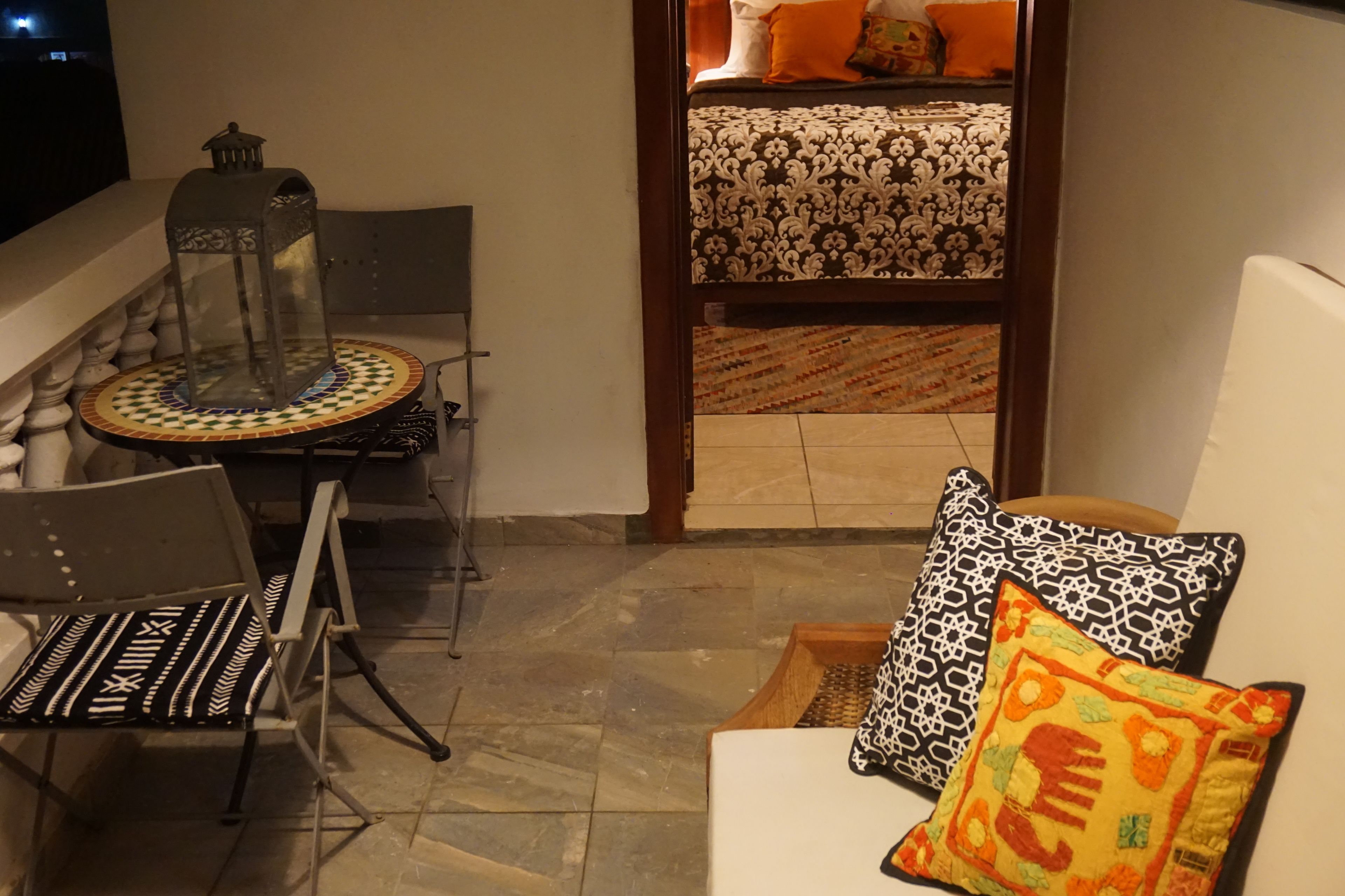 Un balcon accueillant avec une table à manger, des chaises et un canapé agrémenté de coussins à motifs.
