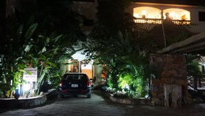 A paved pathway leading to a building with a sign indicating a party center and restaurant bar. - Accra Royal Castle Apartments & Suites (Kwabenya)