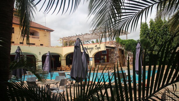 A pool area with lounge chairs and umbrellas, a building labeled "Abanga Spa," and a stone wall. - Accra Royal Castle Apartments & Suites (Kwabenya)