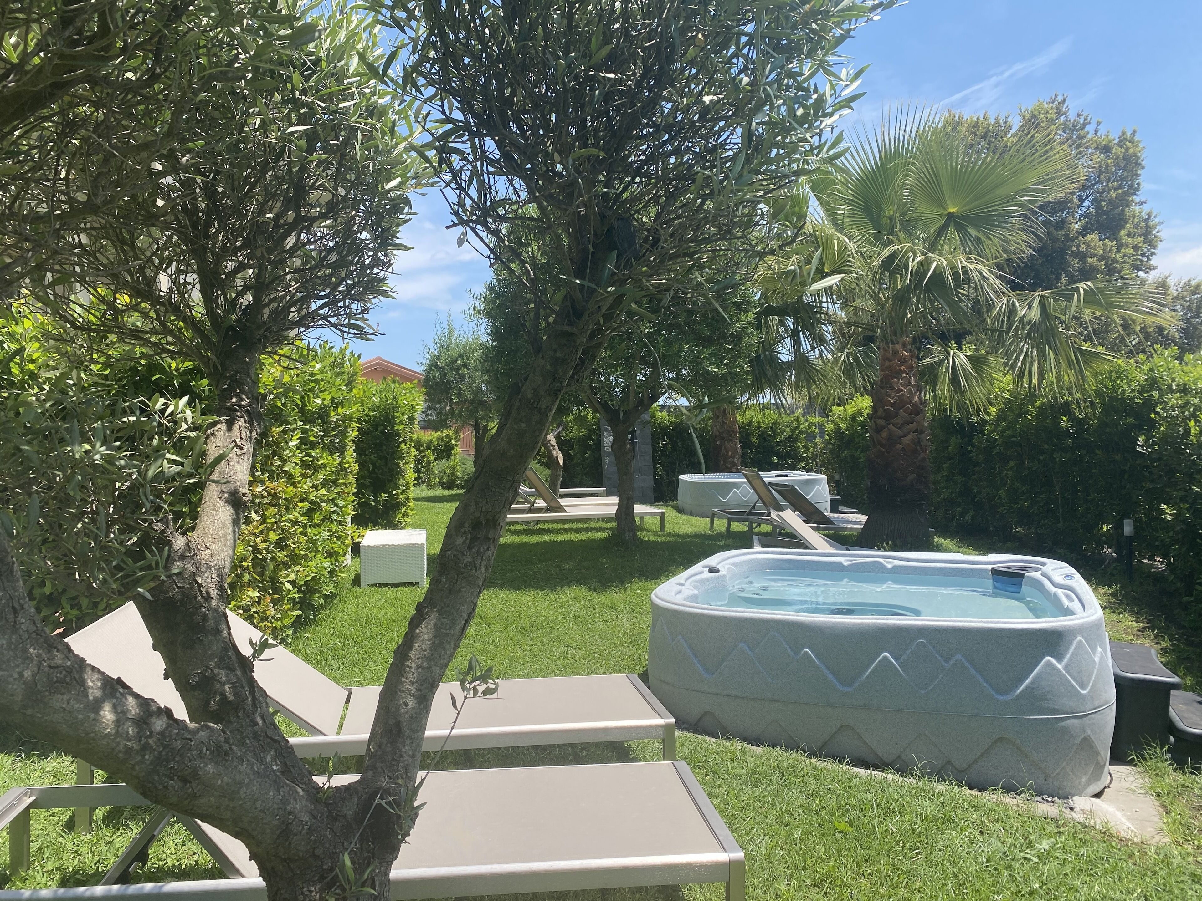 A backyard with a hot tub, lounge chairs, and a well-maintained lawn.