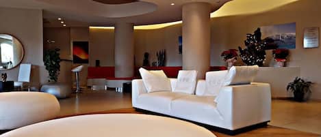 A spacious lobby with a white sofa, a large mirror, and a red accent wall.