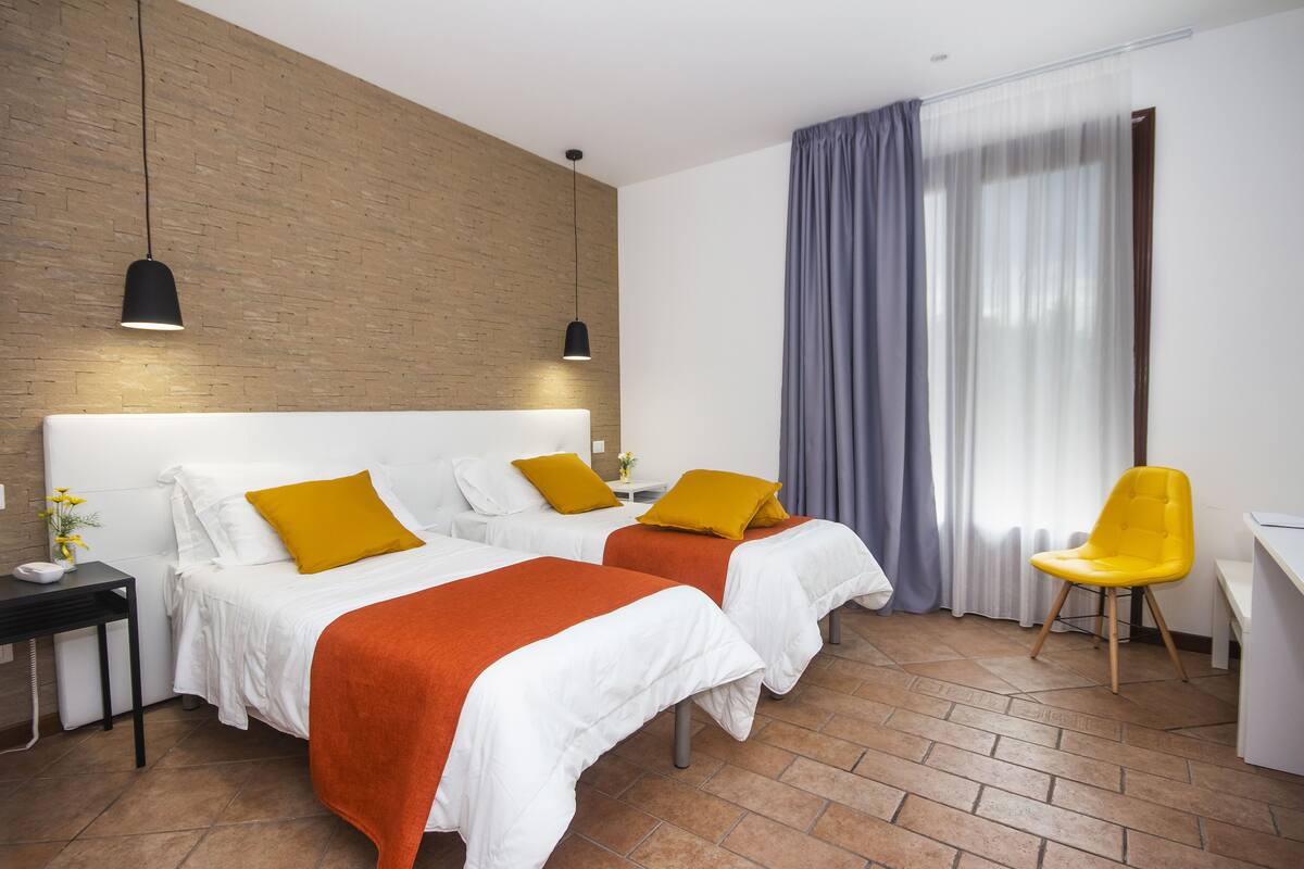 A hotel room with two beds, a desk, and a chair.