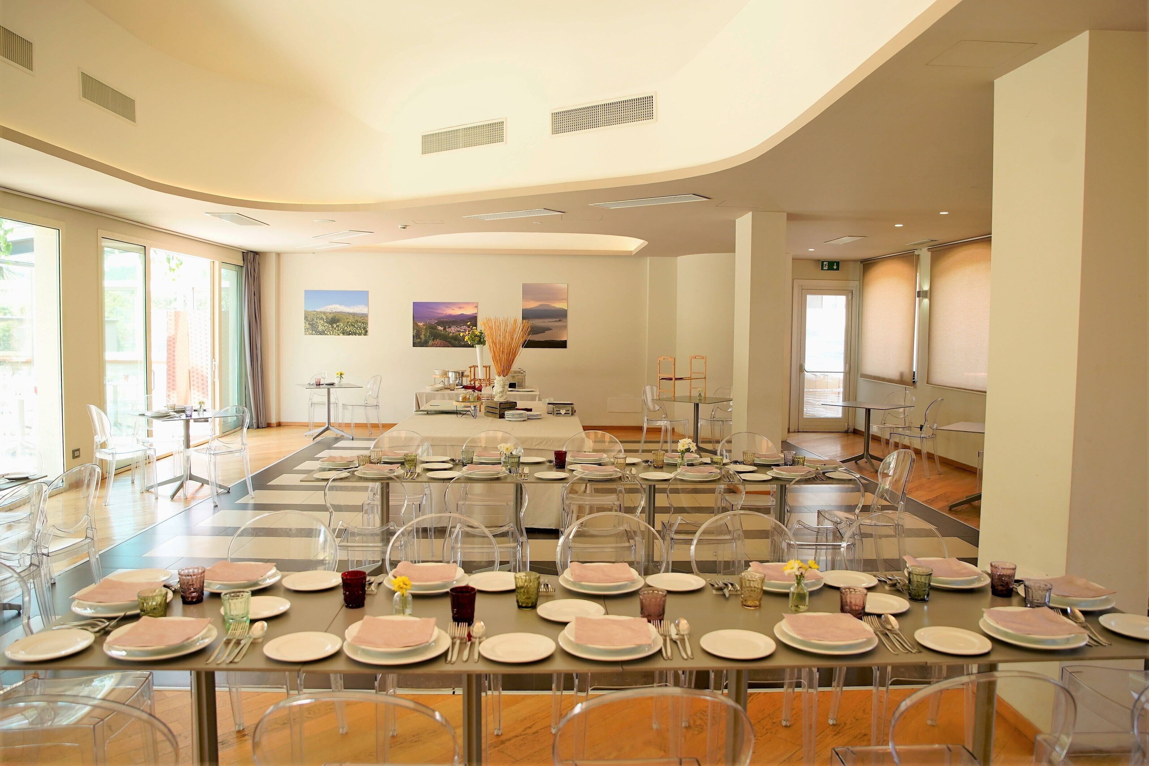 A spacious dining area with clear chairs, neatly set tables, and large windows allowing natural light.
