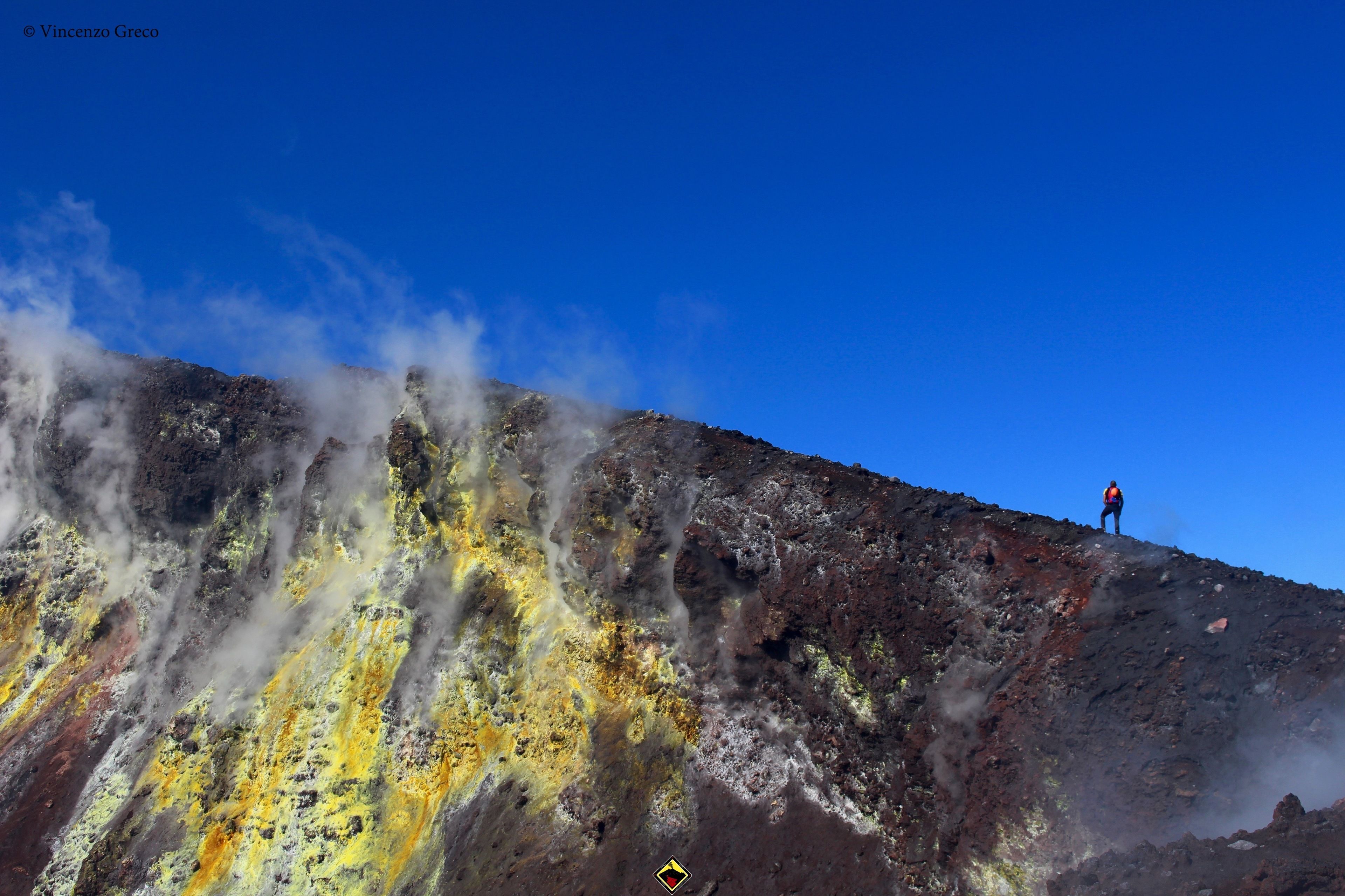 A person standing on a rocky mountain with steam rising from the ground.