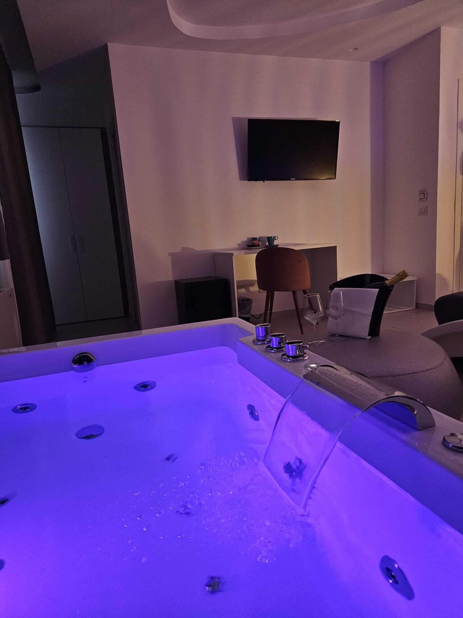 A modern bathroom with a large bathtub, a mirror, and a sink.