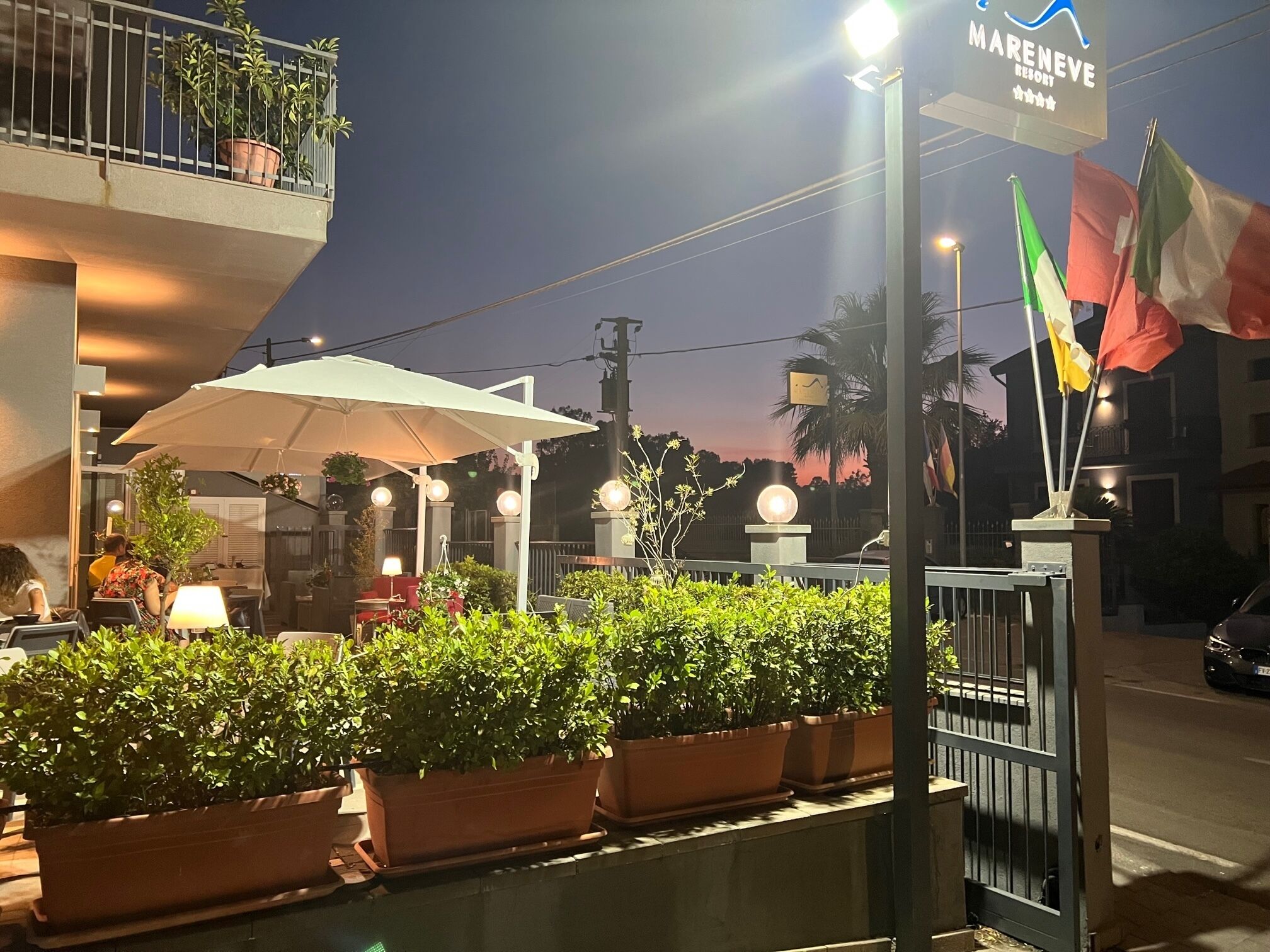 A Mareneve Resort outdoor seating area with potted plants, umbrellas, and a signboard.