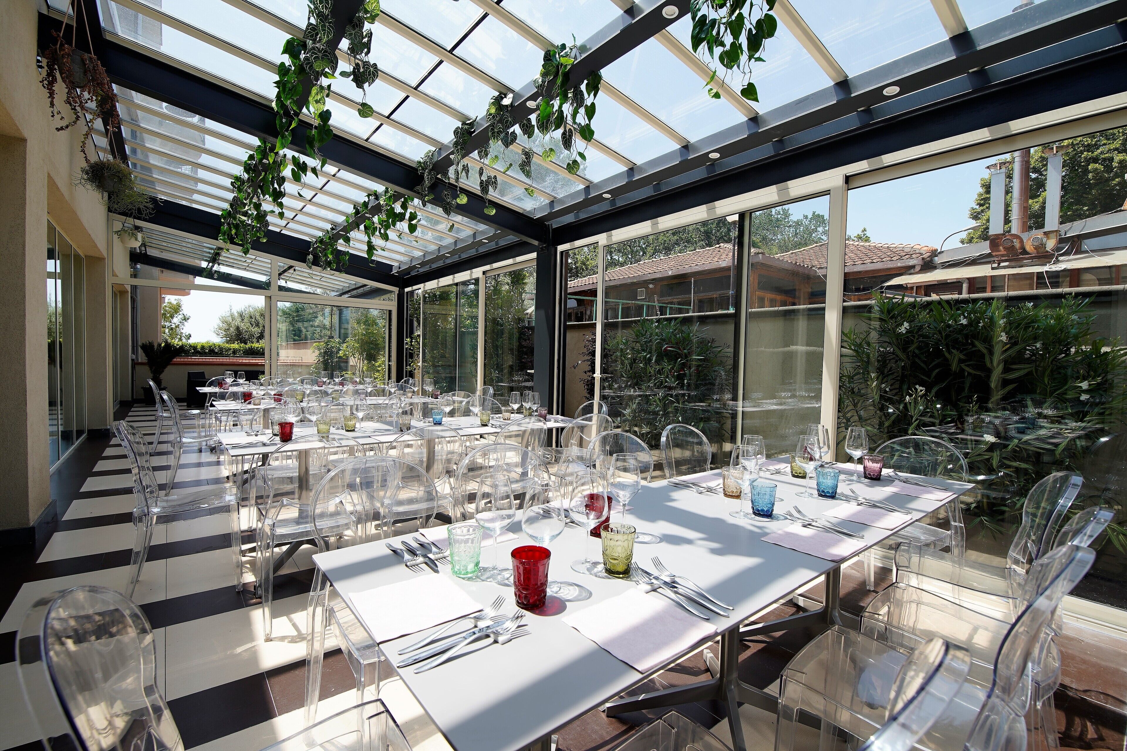 A conservatory with transparent ceiling, clear chairs, and tables set for dining.