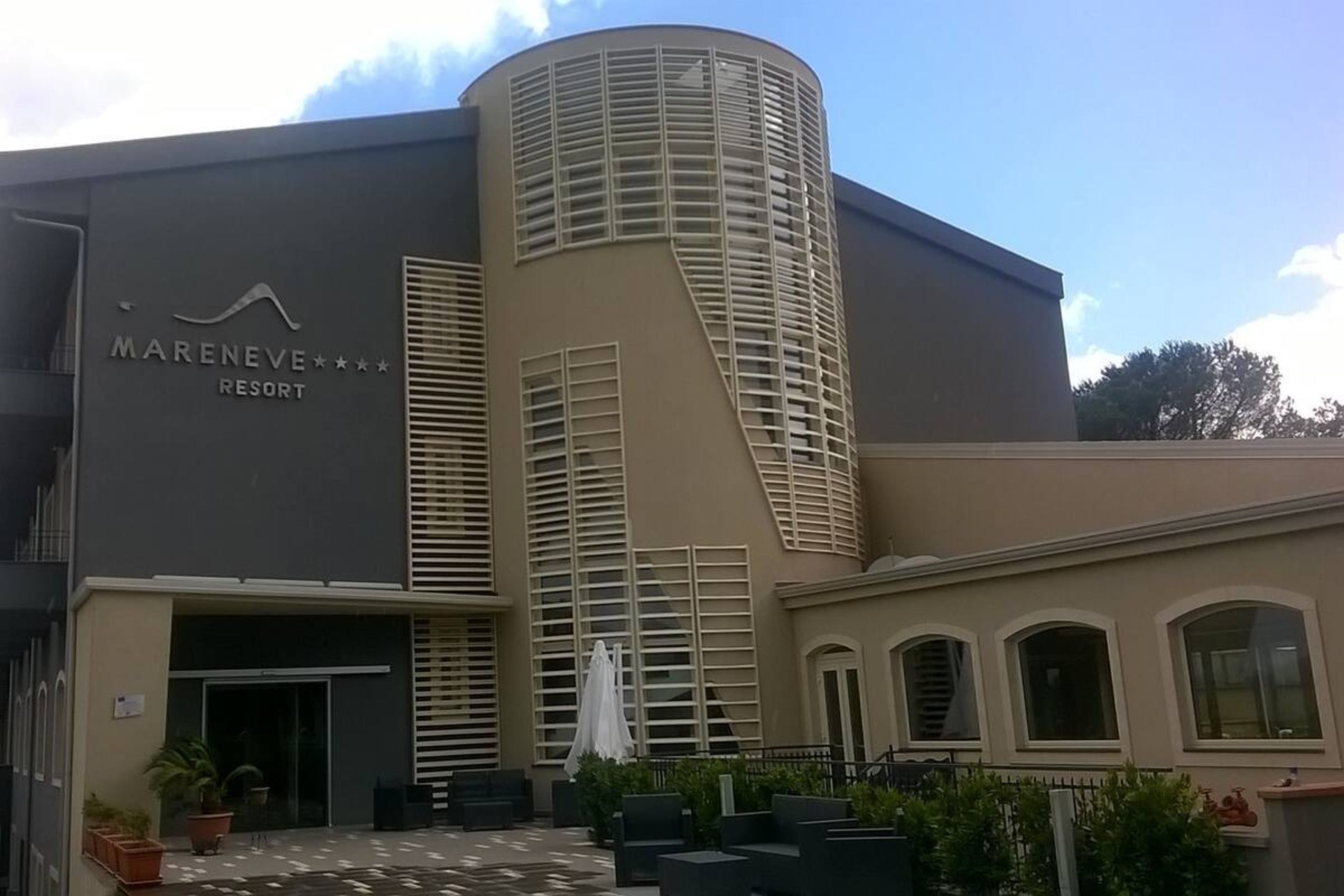 Un bâtiment moderne à la façade incurvée, portant l’inscription « Marenove Resort ».