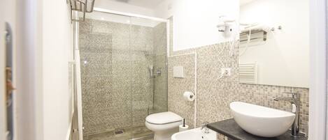 A modern bathroom with a glass-enclosed shower, a white toilet, and a large vessel sink.