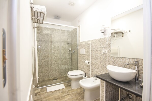 A modern bathroom with a glass-enclosed shower, a white toilet, and a large vessel sink.