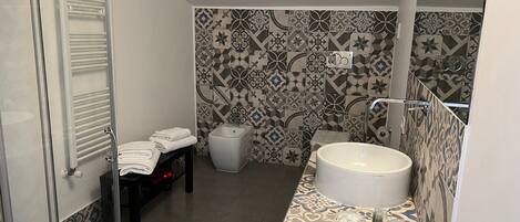 A bathroom with a glass shower enclosure, a white sink, and patterned tiles.