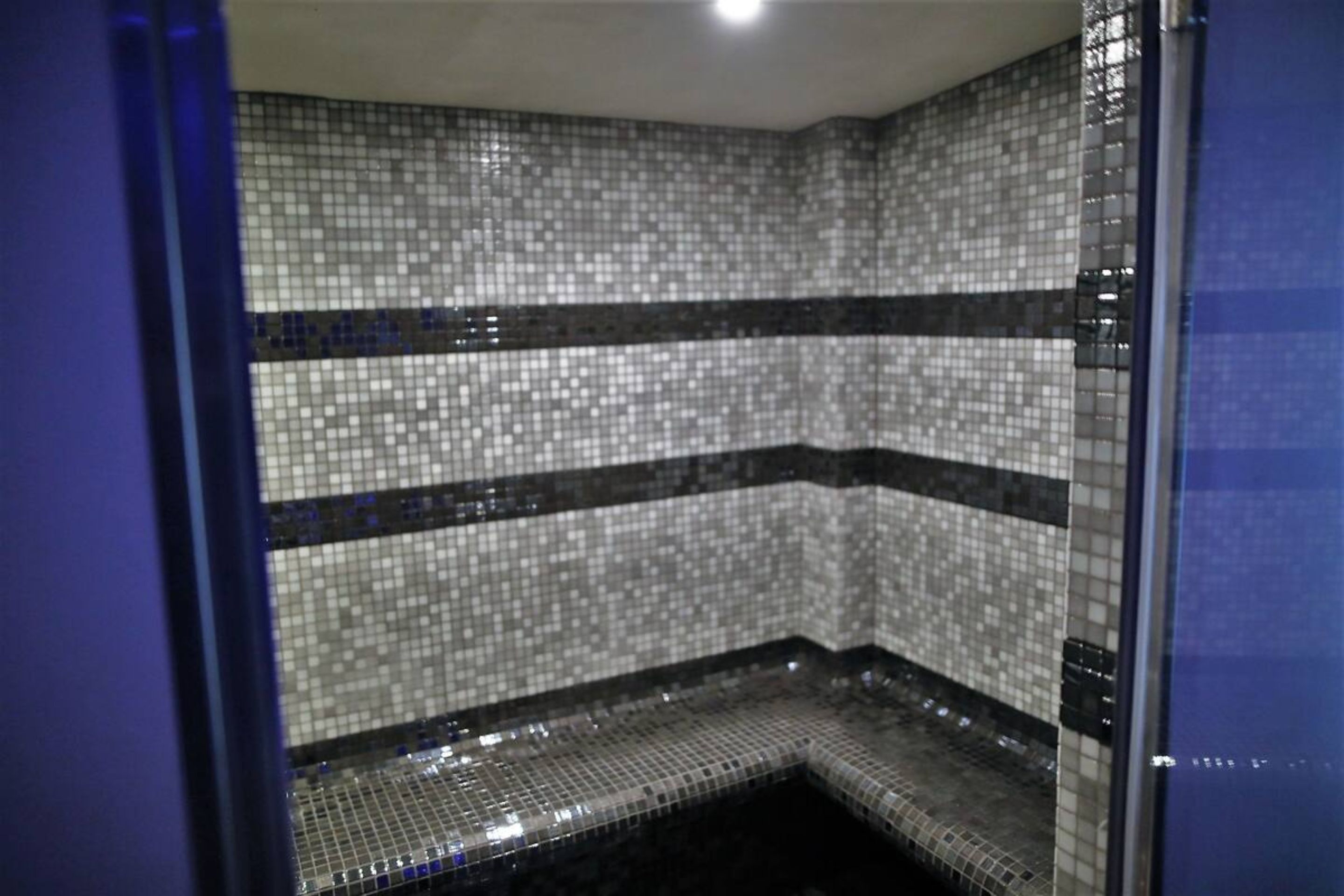 Une zone de douche carrelée, avec un design d’angle et un drain apparent.