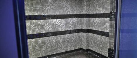 A tiled shower area with a corner design and a visible drain.