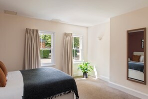 A bedroom with a bed, two windows with curtains, a potted plant, and a mirror on the wall. - SACO Reading - Castle Crescent (Reading)