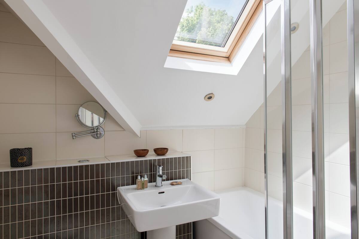 Un baño moderno con tragaluz, un lavamanos blanco y una bañera.