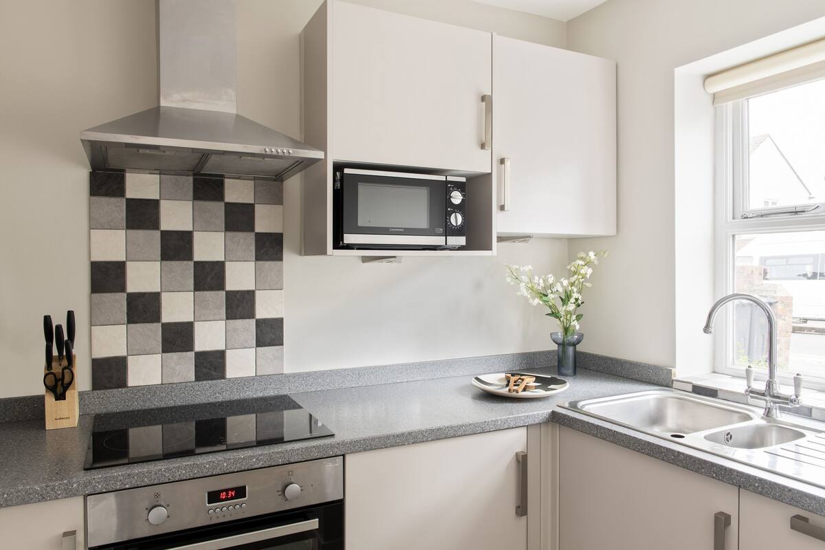 Una cocina moderna con microondas, estufa y salpicadero a cuadros.