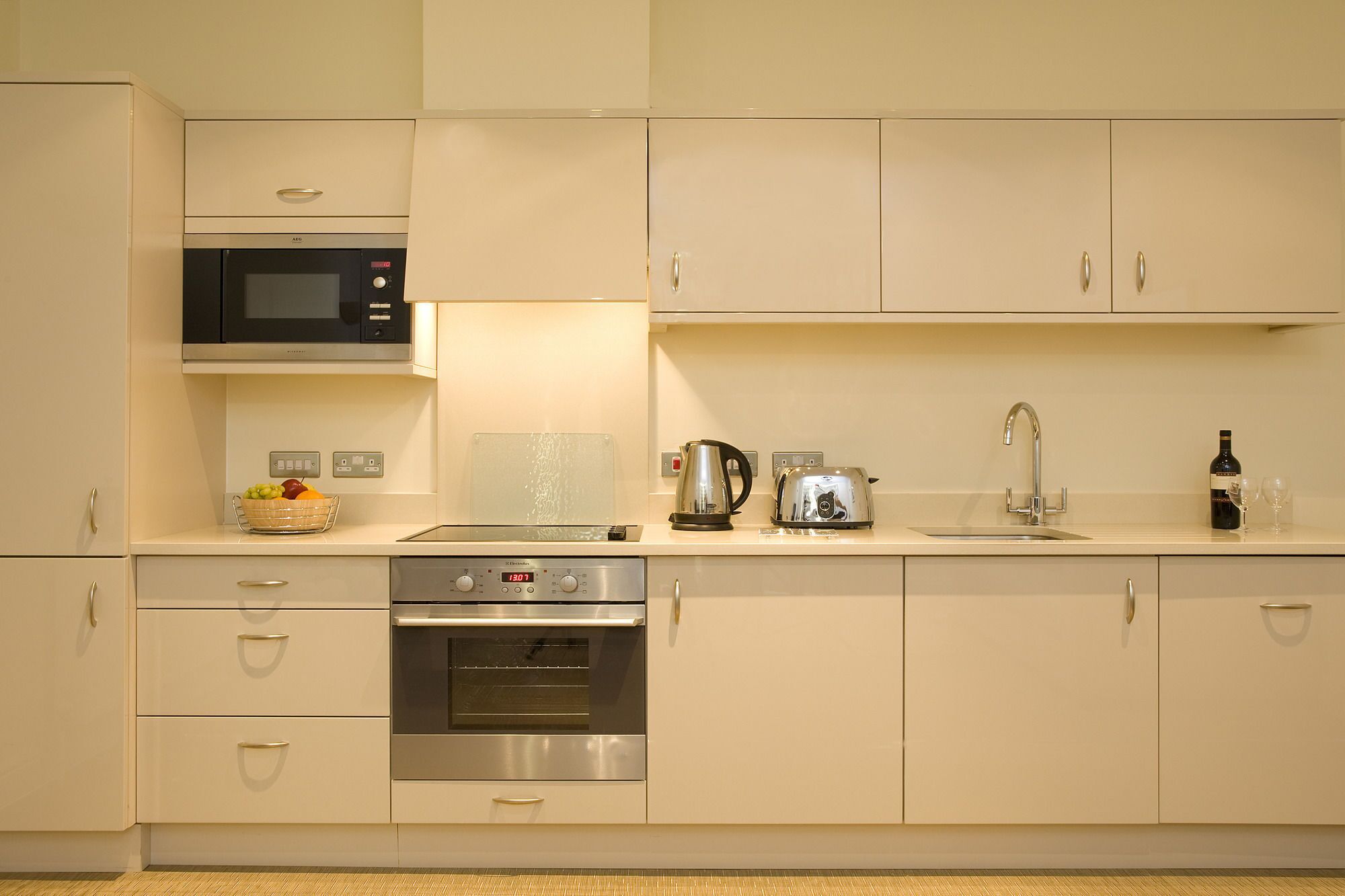 A modern kitchen with stainless steel appliances, a microwave, a kettle, a toaster, and a sink.
