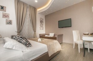 Een moderne hotelkamer met een bed, een bank, een televisie en een eethoek.