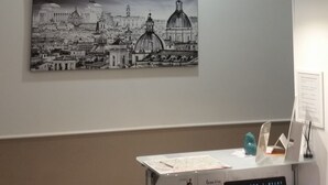 A modern office space with a desk, laptop, and a framed cityscape photograph on the wall. - Elenoire Rooms & Suite (Rome)