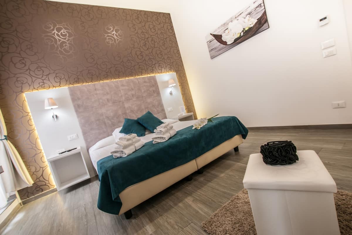 A modern bedroom with a bed, bedside tables, and a small white nightstand.