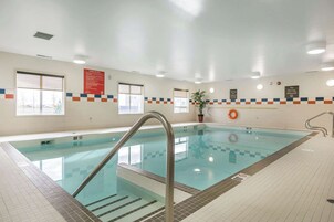 Una piscina interior con agua cristalina, paredes con azulejos y una silla para salvavidas.
