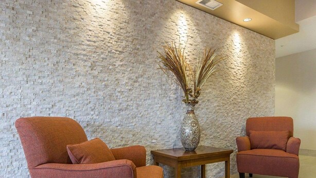 Un vestíbulo con dos sillones y una mesita con un jarrón de plantas secas.
