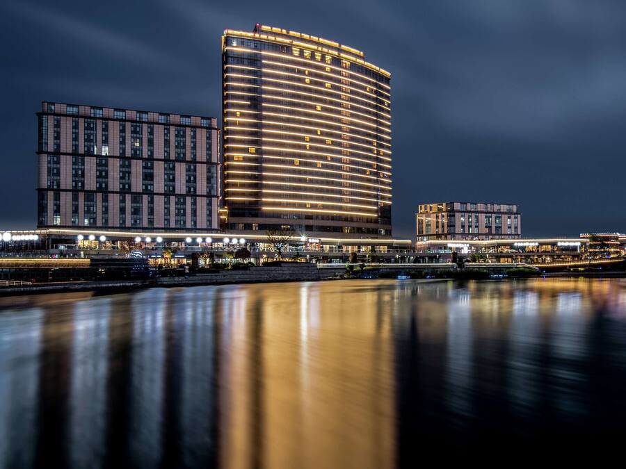 Un hotel moderno con fachada curva, varios pisos y vista al agua.