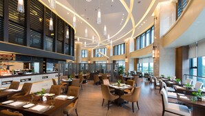 Un restaurant spacieux avec de hauts plafonds, un éclairage moderne et plusieurs espaces de restauration.