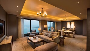 Une chambre d’hôtel moderne dotée d’un grand canapé, d’un coin repas et d’une télévision.