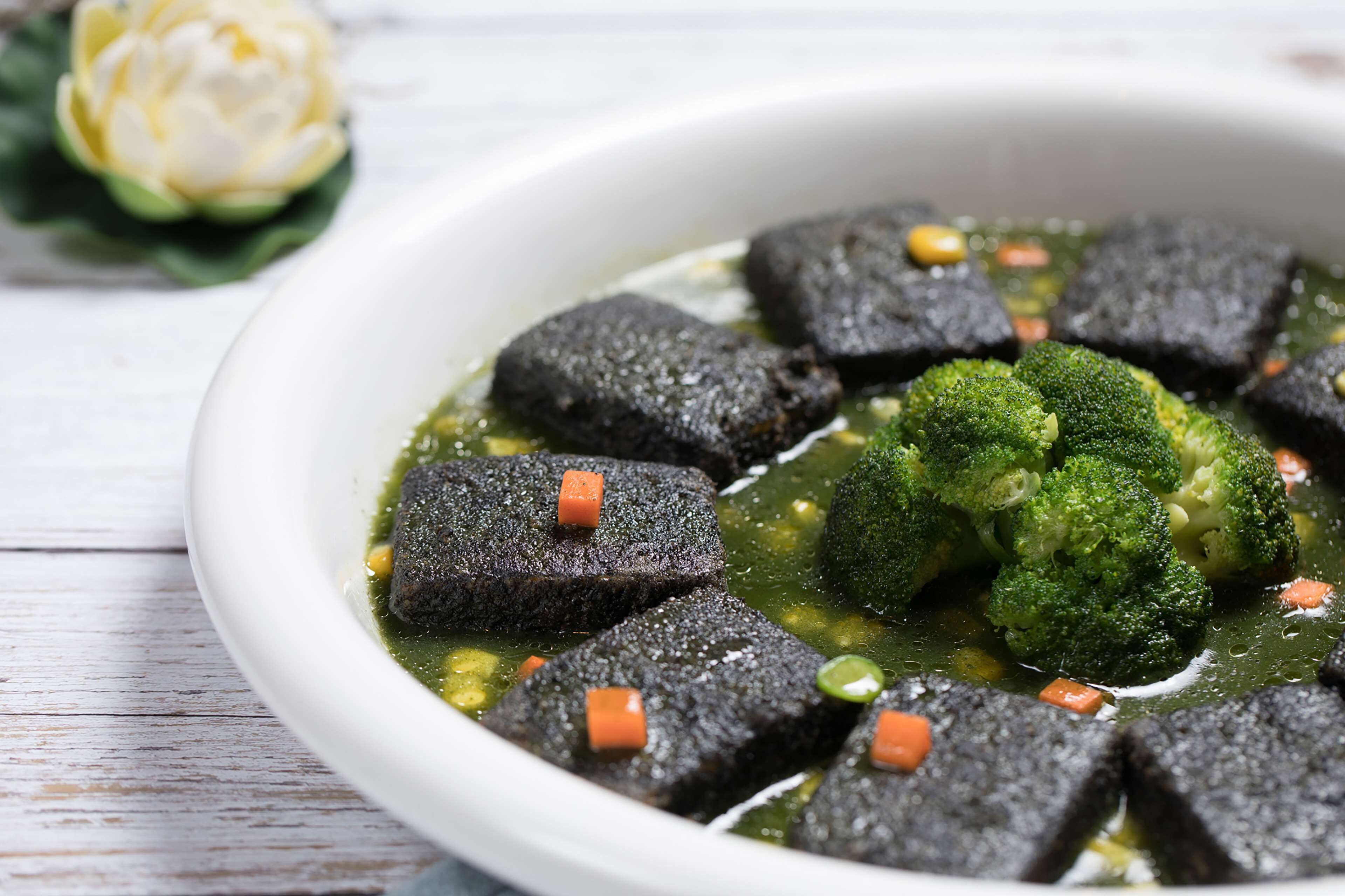 Een kom met donkere groente, broccoli en blokjes wortel.