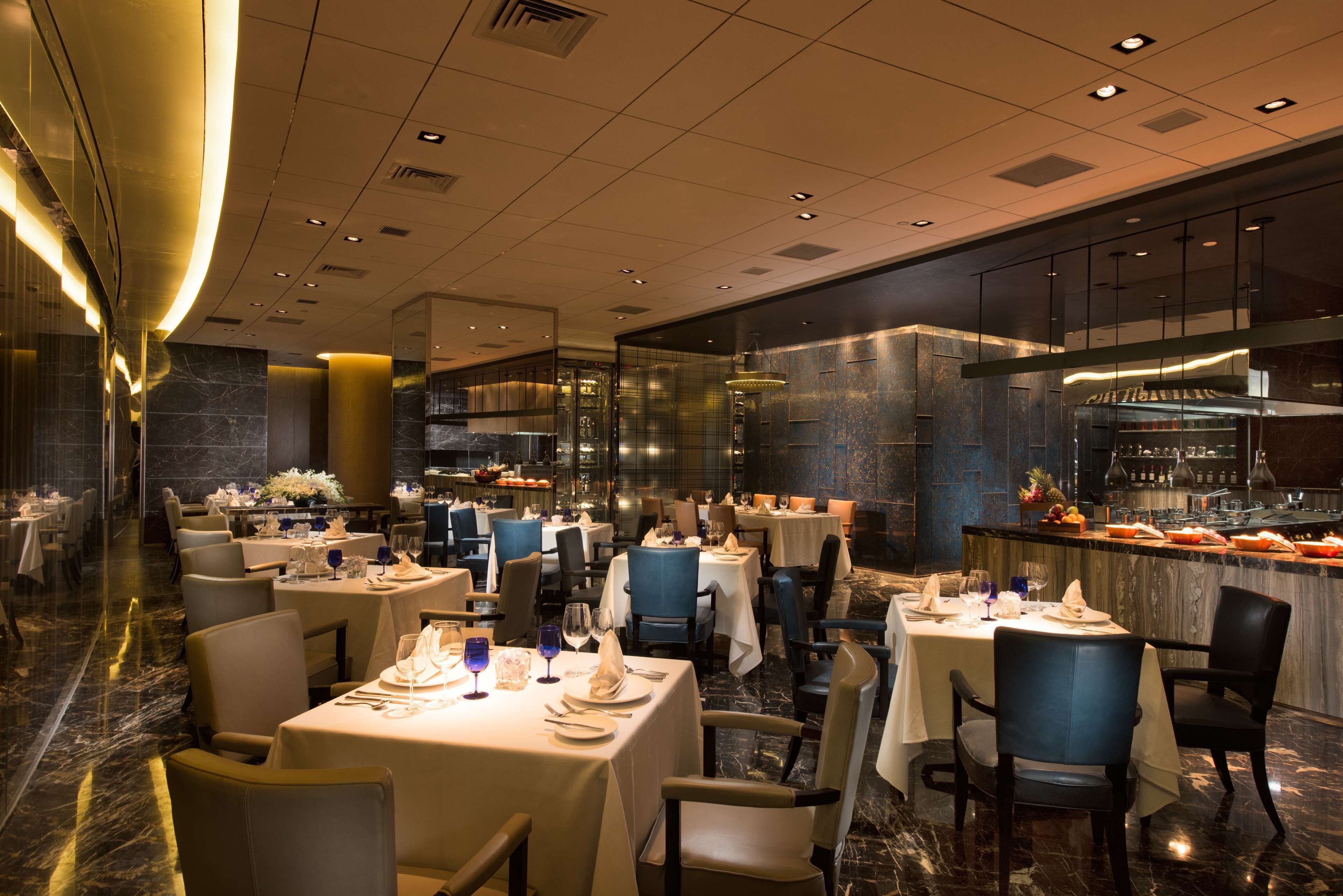 A spacious restaurant with multiple dining tables, chairs, and a bar area.