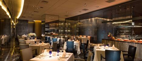 A spacious restaurant with multiple dining tables, chairs, and a bar area.